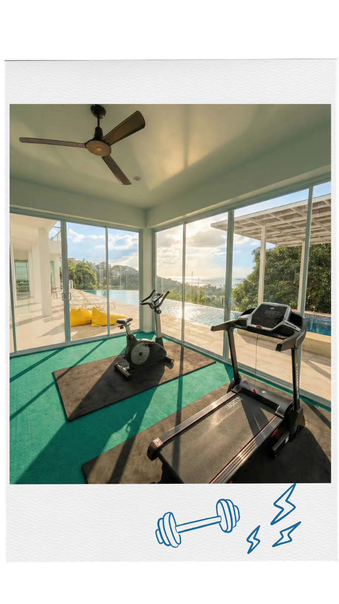 Indoor gym with exercise bike and treadmill overlooking an outdoor pool and scenic view.