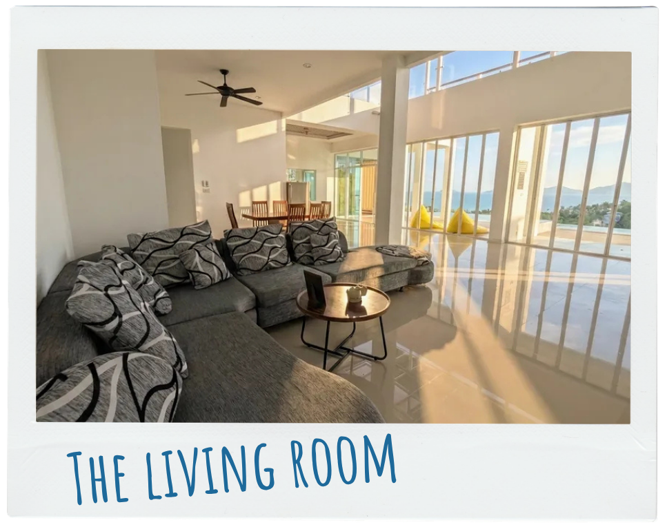 Bright modern living room with a gray sectional sofa, a small round table, and large windows showing outdoor view.